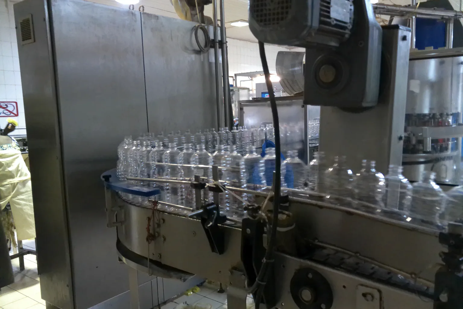 Clear plastic bottles moving through a curved conveyor section inside an industrial bottling facility