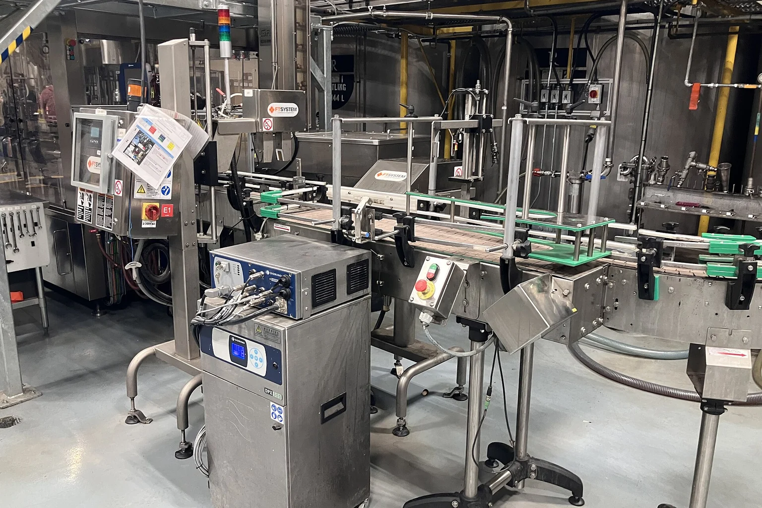 Stainless steel industrial bottling equipment and conveyor inside a working production facility