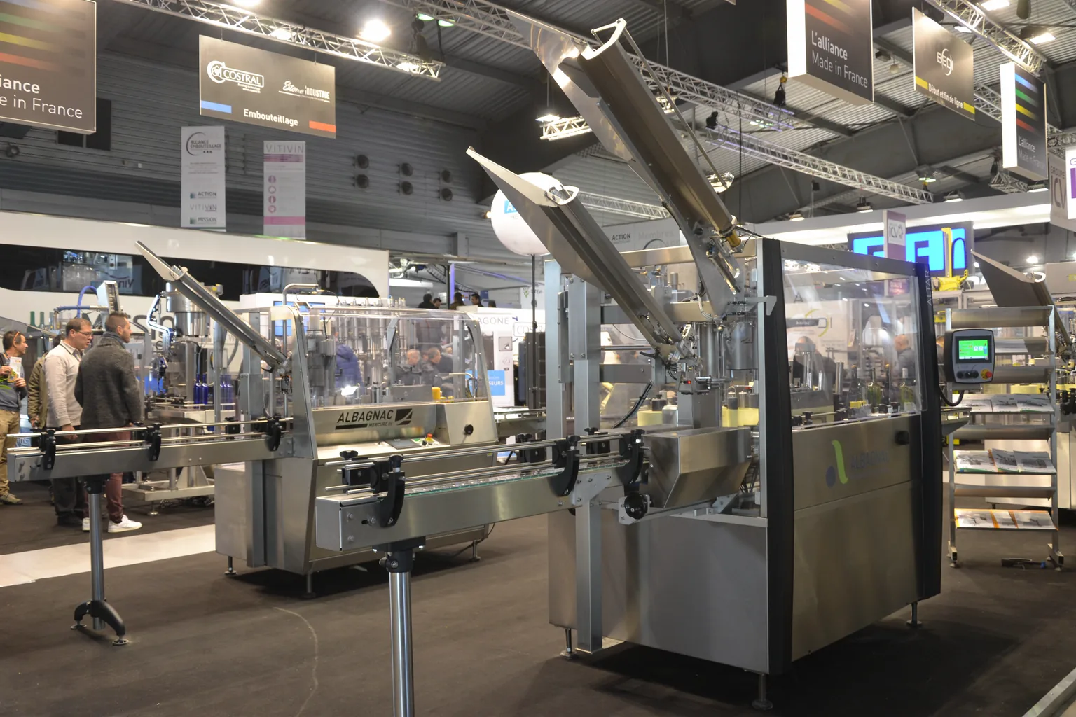 Complete stainless steel bottling line displayed with conveyors, filling equipment and control panels at an industrial trade show
