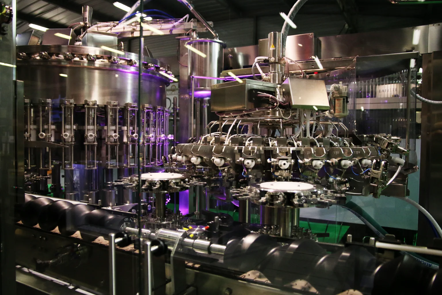 Stainless steel rotary rinser and filler installed on an industrial beverage bottling line